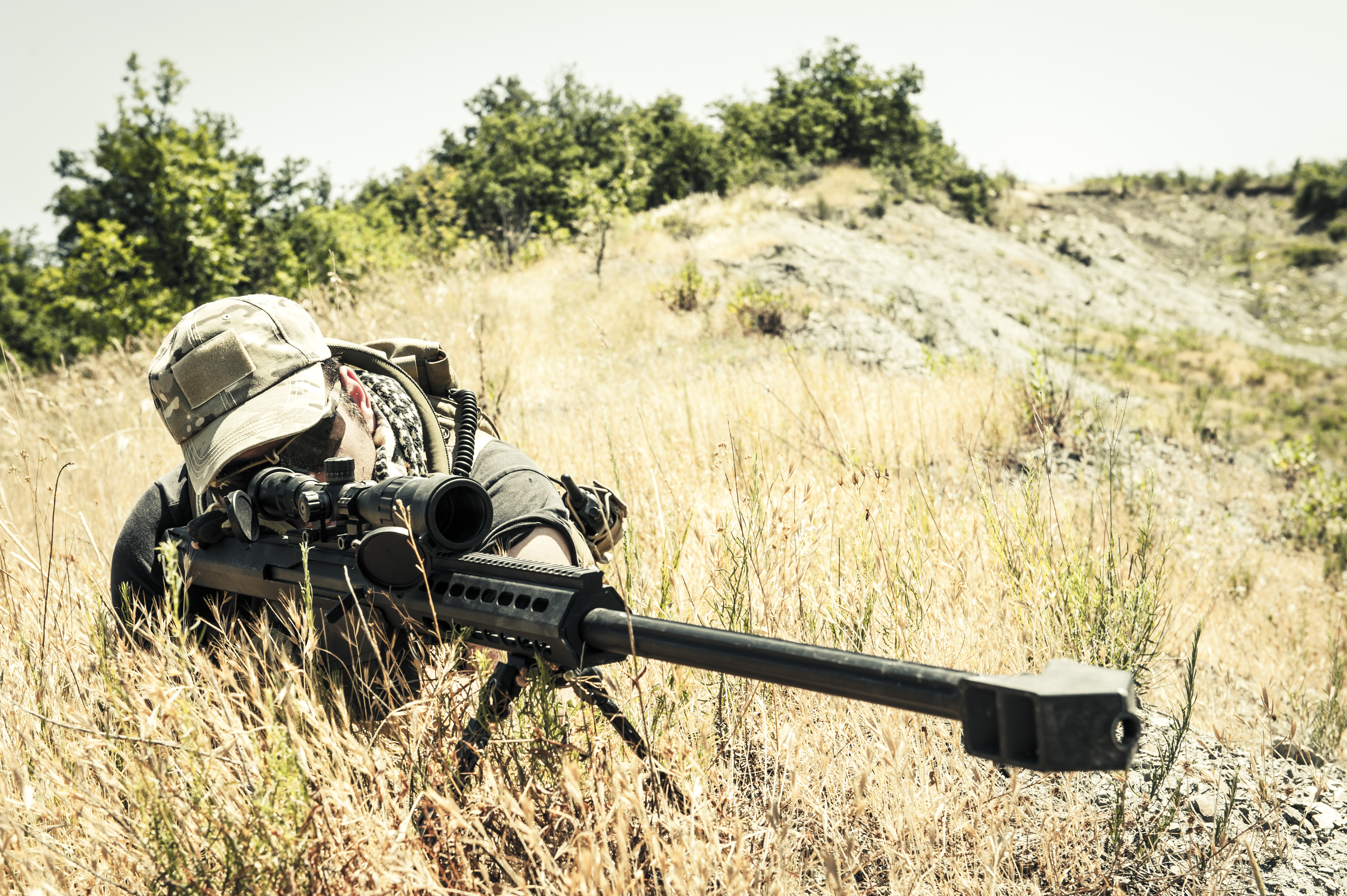 Sniper Aiming withScharfschütze im Gras Barrett M82A1 Precision Rifle in Arid Location